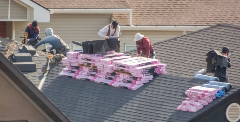 Roofers installing shingles on residential roof